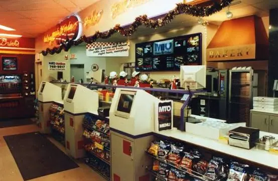 Customer building a Made-to-Order meal on a Sheetz touchscreen kiosk in-store, mid-order with topping options on screen.